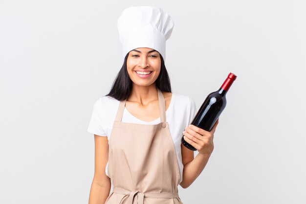 Jolie femme hispanique de chef avec une bouteille de vin