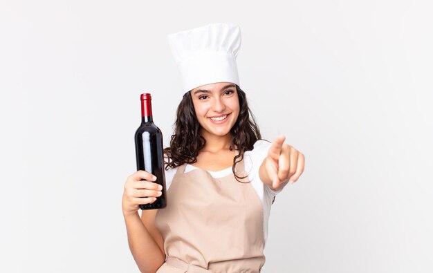 Jolie femme hispanique de chef avec une bouteille de vin