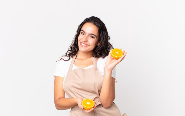 Jolie femme hispanique de chef préparant un jus d'orange