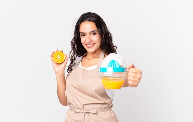 Jolie femme hispanique de chef préparant un jus d'orange