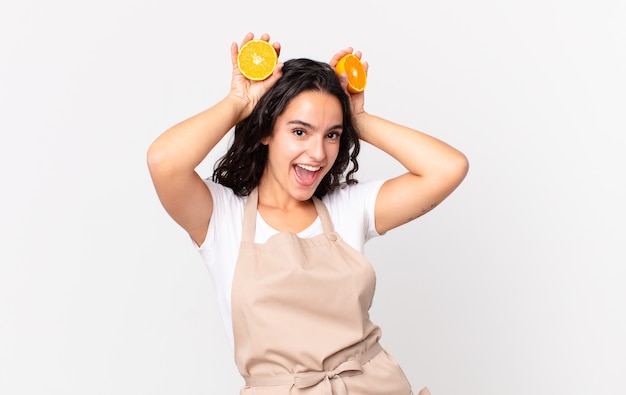 Jolie femme hispanique de chef préparant un jus d'orange