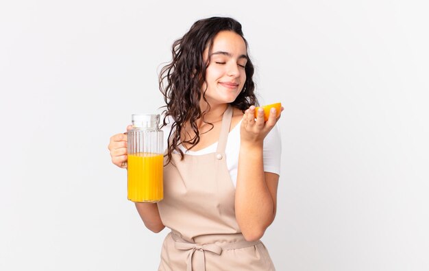 Jolie femme hispanique de chef préparant un jus d'orange