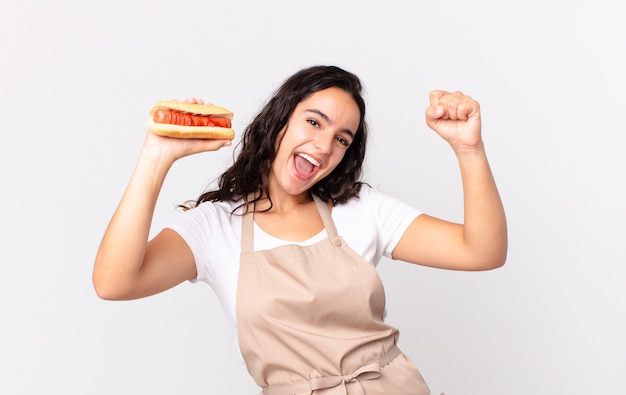 Jolie femme hispanique de chef tenant un hot-dog