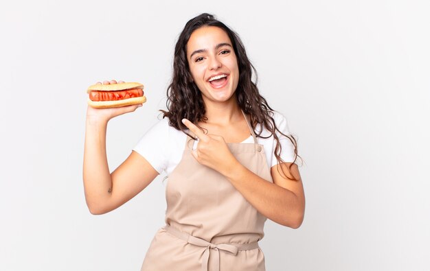 Jolie femme hispanique de chef tenant un hot-dog