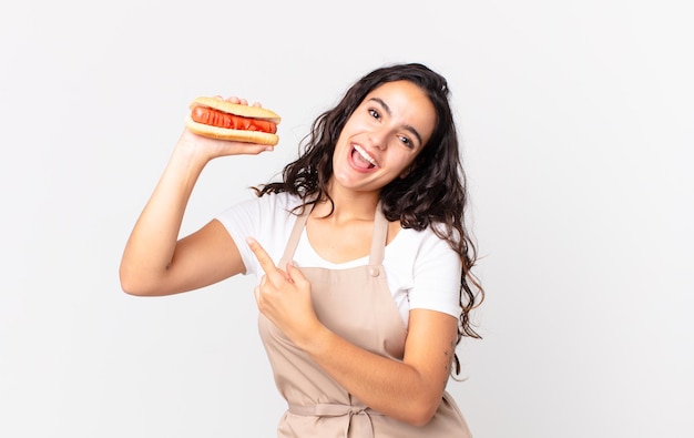 Jolie femme hispanique de chef tenant un hot-dog