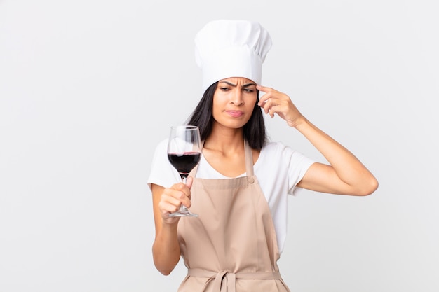 Jolie femme hispanique de chef tenant un verre de vin