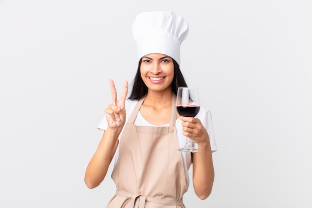 Jolie femme hispanique chef tenant un verre de vin