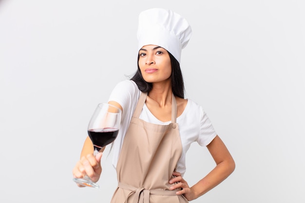 Jolie femme hispanique chef tenant un verre de vin