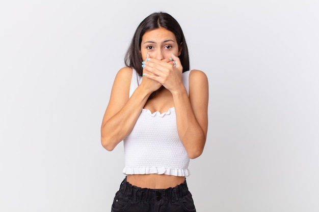 Jolie femme hispanique couvrant la bouche avec les mains avec un choc