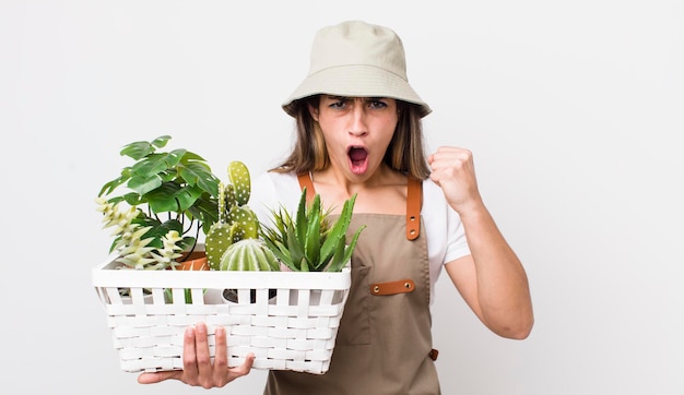 Jolie femme hispanique criant agressivement avec une expression de colère plantes et concept de jardinage