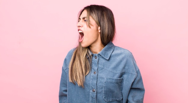 Jolie femme hispanique criant furieusement criant agressivement à l'air stressé et en colère