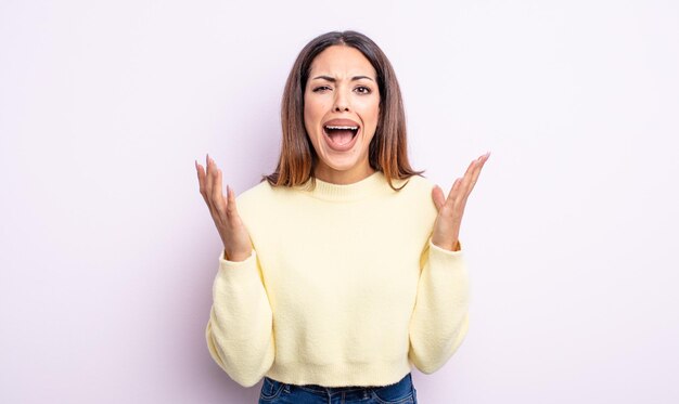 Jolie femme hispanique criant furieusement, se sentant stressée et ennuyée avec les mains en l'air disant pourquoi moi