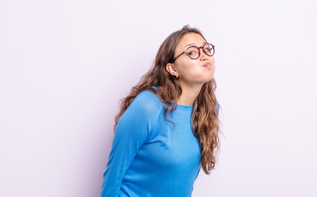 Jolie femme hispanique avec une expression maladroite, folle et surprise, des joues gonflées, se sentant bourrée, grosse et pleine de nourriture