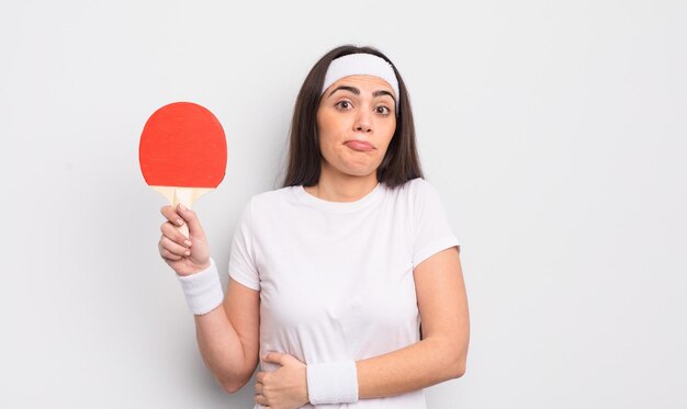 Jolie femme hispanique haussant les épaules, se sentant confuse et incertaine. notion de ping-pong