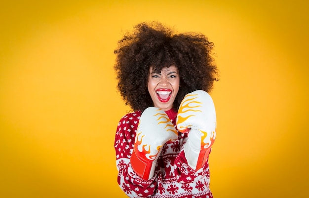 jolie femme hispanique latine à noël, avec des gants de boxe. Fond jaune