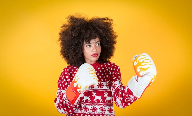 Photo jolie femme hispanique latine à noël, avec des gants de boxe. fond jaune