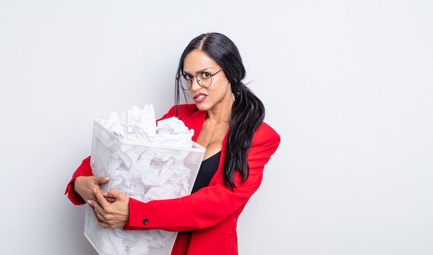 Jolie femme hispanique à la perplexité et confus concept poubelle boules de papier