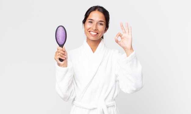 Jolie femme hispanique portant un peignoir et tenant une brosse à cheveux