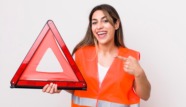 Jolie femme hispanique qui a l'air excitée et surprise en montrant le concept de triangle de voiture latérale