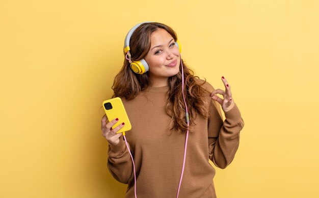 Jolie femme hispanique à la recherche arrogante, réussie, positive et fière. casque et concept de smartphone