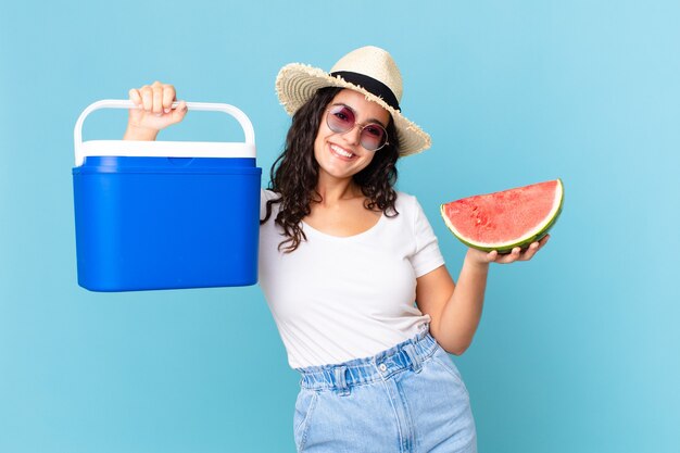 Jolie femme hispanique avec un réfrigérateur portable et une pastèque