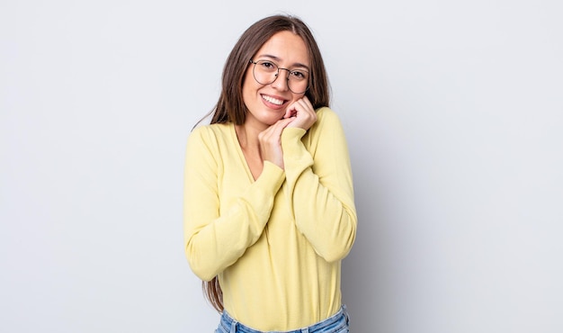 Jolie femme hispanique se sentant amoureuse et ayant l'air mignonne, adorable et heureuse, souriant de manière romantique avec les mains à côté du visage