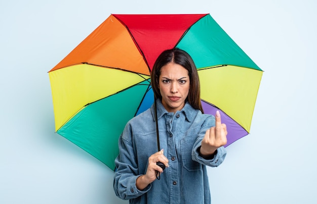 Jolie femme hispanique se sentant en colère, agacée, rebelle et agressive. concept de parapluie