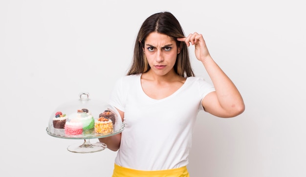 Photo jolie femme hispanique se sentant confuse et perplexe montrant que vous êtes un concept de gâteaux faits maison fou