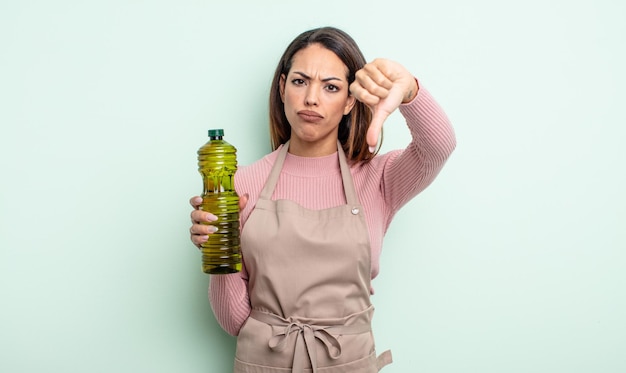 Jolie femme hispanique se sentant croisée, montrant les pouces vers le bas. concept d'huile d'olive