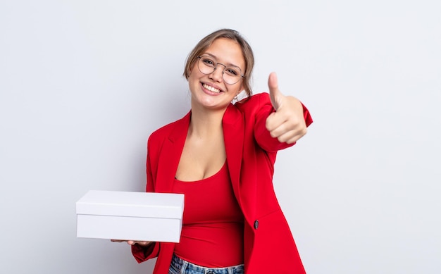 Jolie femme hispanique se sentant fière, souriante positivement avec le pouce levé. concept de produit d'emballage