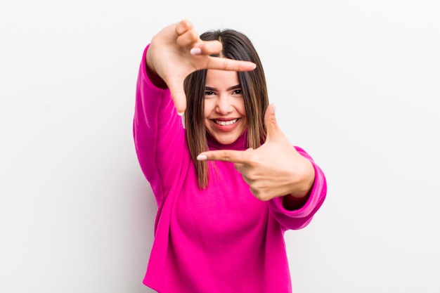 Jolie femme hispanique se sentant heureuse amicale et positive souriante et faisant un portrait ou un cadre photo avec les mains