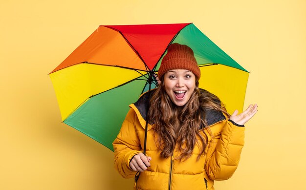 Jolie femme hispanique se sentant heureuse et étonnée de quelque chose d'incroyable. concept de parapluie