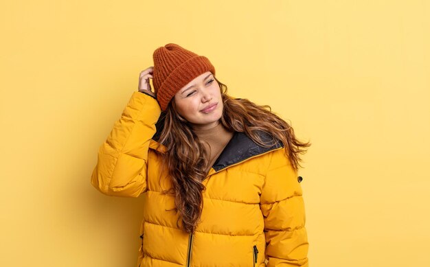 Jolie femme hispanique se sentant perplexe et confuse, se grattant la tête. vêtements d'hiver