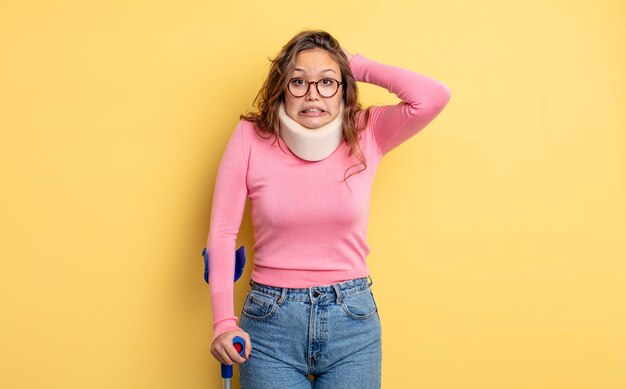 Jolie femme hispanique se sentant stressée, anxieuse ou effrayée, les mains sur la tête. accident de béquille et de collier