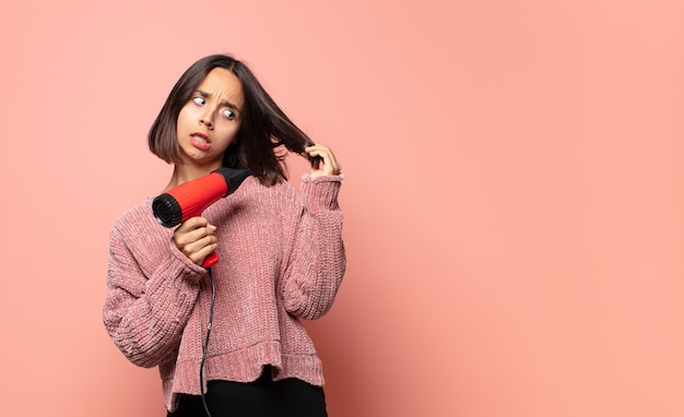 Jolie femme hispanique avec un sèche-cheveux