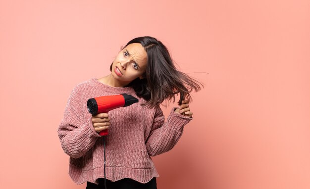 Jolie femme hispanique avec un sèche-cheveux