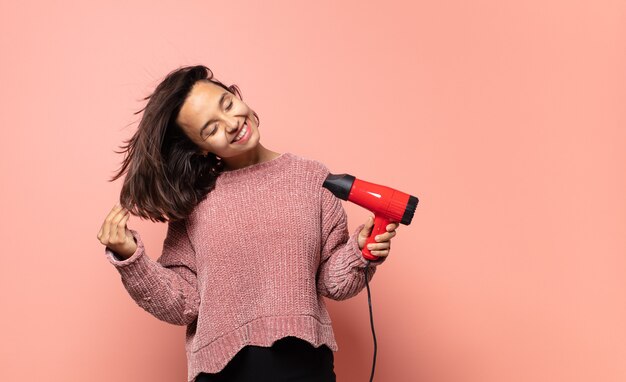 Jolie femme hispanique avec un sèche-cheveux