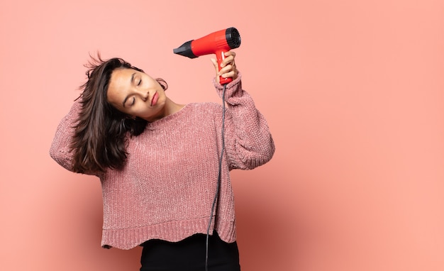 Jolie femme hispanique avec un sèche-cheveux