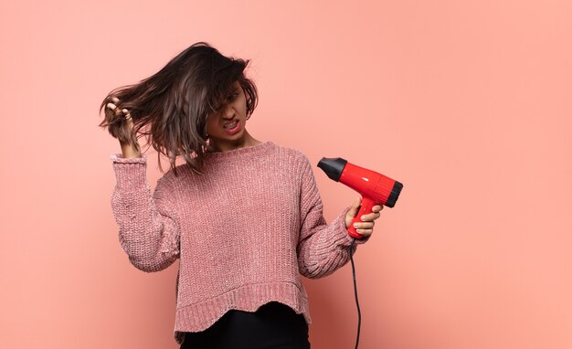 Jolie femme hispanique avec un sèche-cheveux