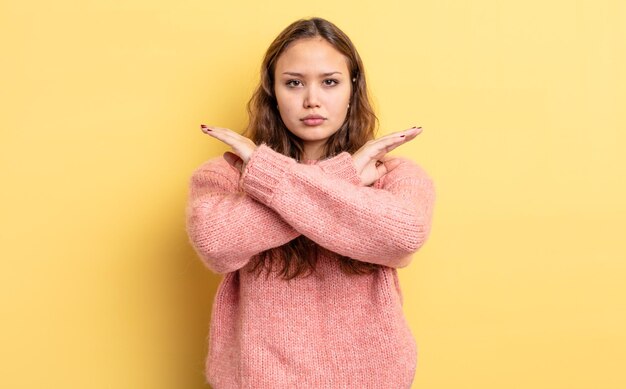 Jolie femme hispanique semblant ennuyée et malade de votre attitude, en disant assez ! les mains croisées devant, vous disant d'arrêter