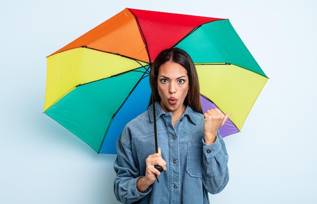 Jolie femme hispanique semblant étonnée d'incrédulité. concept de parapluie