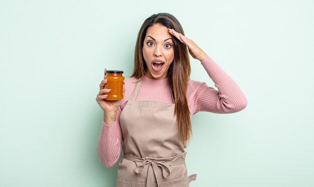 Jolie femme hispanique semblant heureuse, étonnée et surprise. concept de confiture de pêche