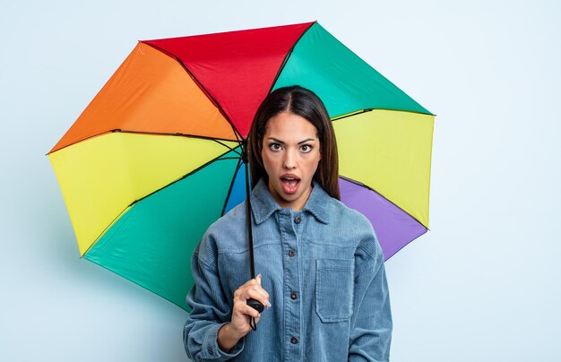 Jolie femme hispanique semblant très choquée ou surprise. concept de parapluie