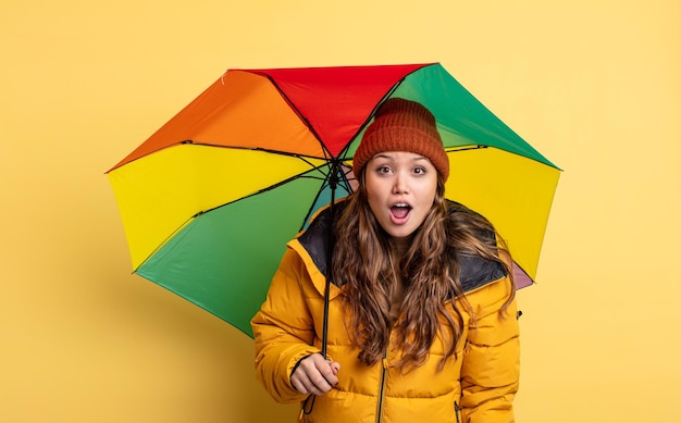 Jolie femme hispanique semblant très choquée ou surprise. notion de parapluie