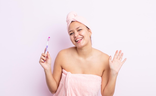 Jolie femme hispanique souriant joyeusement en agitant la main vous accueillant et vous saluant concept de brosse à dents