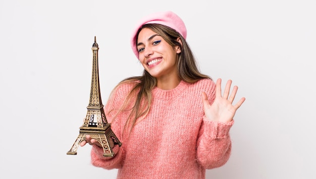 Jolie femme hispanique souriant joyeusement en agitant la main vous accueillant et vous saluant concept france