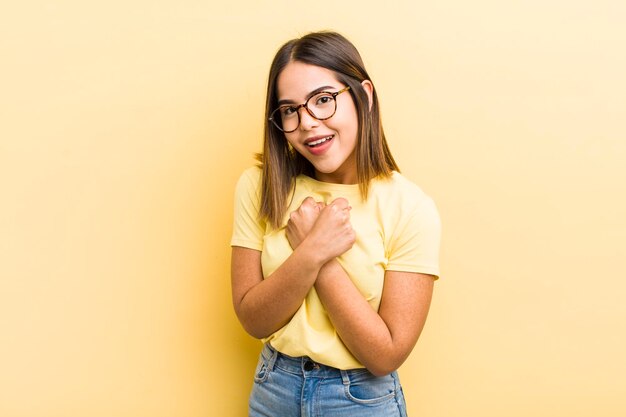 Jolie femme hispanique souriant joyeusement et célébrant avec les poings serrés et les bras croisés se sentant heureux et positif