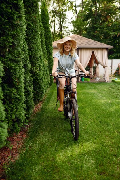 Jolie femme jardinière pose à vélo dans le jardin