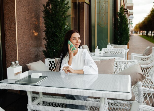 Jolie femme avec un joli sourire parlant sur un téléphone portable tout en se relaxant dans un café.