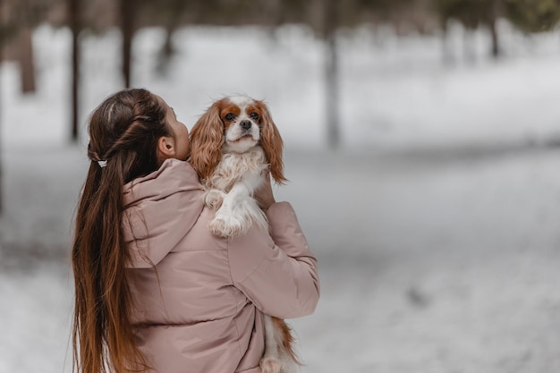 Jolie femme jouant avec un chien dans la forêt du parc d'hiver